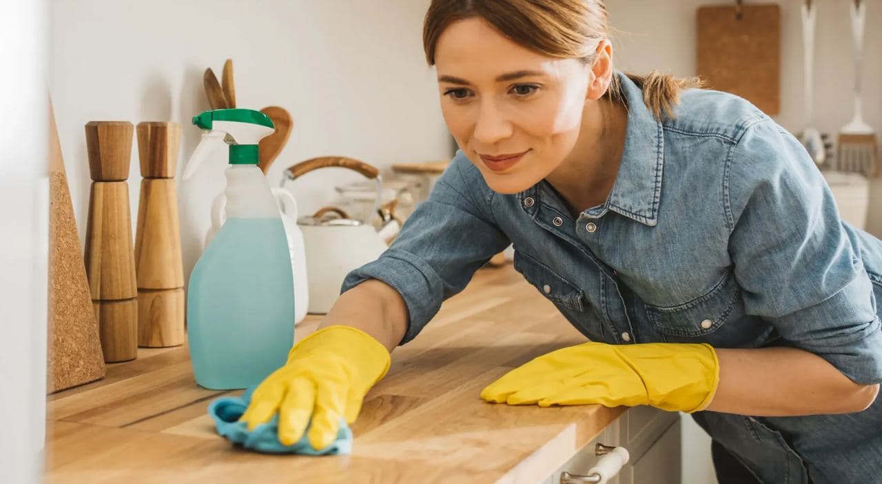 Cleaner in yellow gloves wiping a kitchen counter